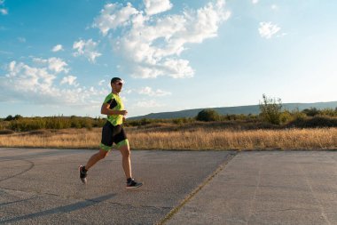 Sabahın erken saatlerinde profesyonel kıyafetlerle koşan triatloncu, maratona hazırlanıyor, spora ve bir maratonun mücadelesine hazırlanıyor.