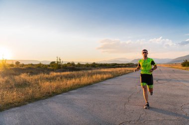 Sabahın erken saatlerinde profesyonel kıyafetlerle koşan triatloncu, maratona hazırlanıyor, spora ve bir maratonun mücadelesine hazırlanıyor.