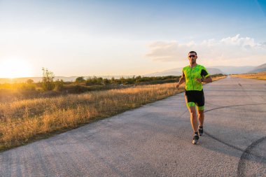 Sabahın erken saatlerinde profesyonel kıyafetlerle koşan triatloncu, maratona hazırlanıyor, spora ve bir maratonun mücadelesine hazırlanıyor.