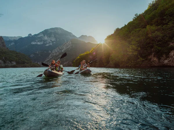 穏やかな川を探索する楽しさとカヤックを楽しむ友人のグループ 牧歌的な夕日の間に森や大規模な自然川渓谷を囲む — ストック写真
