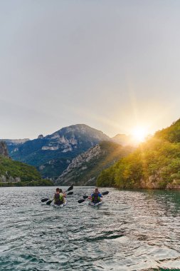 Bir grup arkadaş, sakin nehri, çevresindeki ormanı ve büyük doğal nehir kanyonlarını gezerek gün batımının keyfini çıkarıyorlar.