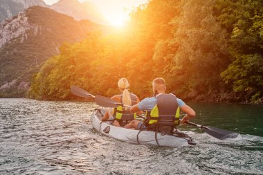 Bir grup arkadaş, sakin nehri, çevresindeki ormanı ve büyük doğal nehir kanyonlarını gezerek gün batımının keyfini çıkarıyorlar.