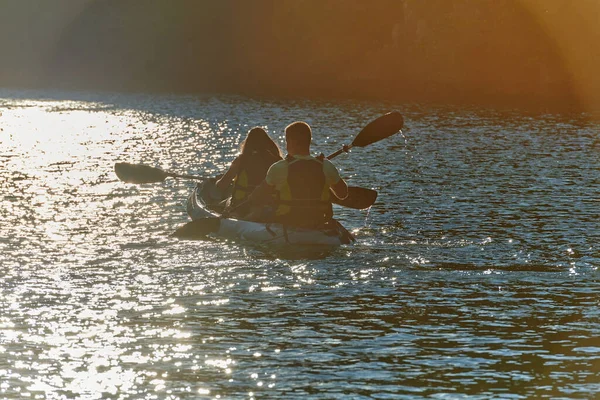 在日落时分 一对年轻夫妇在一条美丽的河流中央享受着田园诗般的独木舟之旅 河流周围环绕着茂密的绿叶 — 图库照片