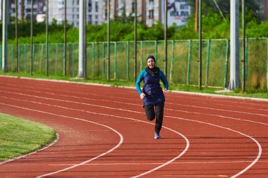 Çarşaf giymiş Müslüman bir kadın, spor kıyafetleriyle maraton koşuyor ve yaklaşan müsabakalara hazırlanıyor.. 