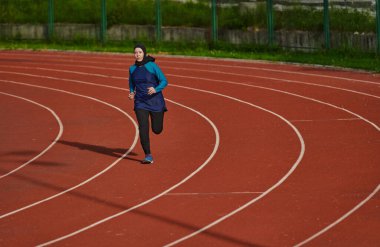 Çarşaf giymiş Müslüman bir kadın, spor kıyafetleriyle maraton koşuyor ve yaklaşan müsabakalara hazırlanıyor.. 