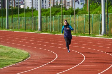 Çarşaf giymiş Müslüman bir kadın, spor kıyafetleriyle maraton koşuyor ve yaklaşan müsabakalara hazırlanıyor.. 