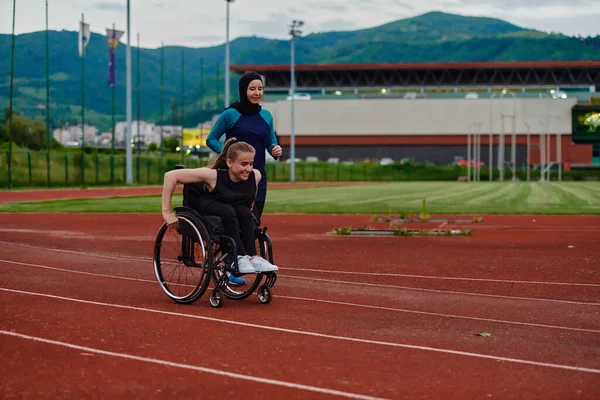 マラソンコースの車椅子の女性と一緒に走るブルカのイスラム教徒の女性 将来の競技会の準備 — ストック写真