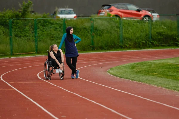 マラソンのハードトレーニングの後に障害のある女性と一緒に休息ブルカを身に着けているイスラム教徒の女性 — ストック写真