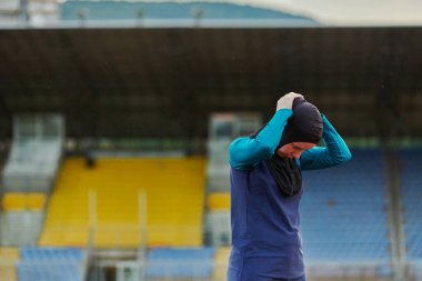 Müslüman bir kadın çarşaf giyiyor, İslami spor kıyafeti, vücut egzersizleri yapıyor, maraton kursunda sıkı bir antrenmandan sonra boynunu, bacaklarını ve sırtını esnetiyor.