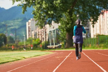 Çarşaf giymiş Müslüman bir kadın, spor kıyafetleriyle maraton koşuyor ve yaklaşan müsabakalara hazırlanıyor.. 