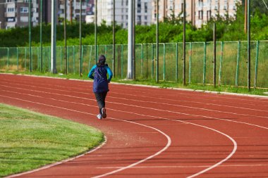 Çarşaf giymiş Müslüman bir kadın, spor kıyafetleriyle maraton koşuyor ve yaklaşan müsabakalara hazırlanıyor.. 