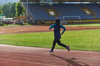 Çarşaf giymiş Müslüman bir kadın, spor kıyafetleriyle maraton koşuyor ve yaklaşan müsabakalara hazırlanıyor.. 