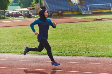 Çarşaf giymiş Müslüman bir kadın, spor kıyafetleriyle maraton koşuyor ve yaklaşan müsabakalara hazırlanıyor.. 