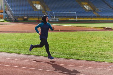 Çarşaf giymiş Müslüman bir kadın, spor kıyafetleriyle maraton koşuyor ve yaklaşan müsabakalara hazırlanıyor.. 