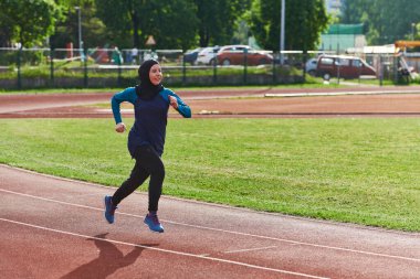 Çarşaf giymiş Müslüman bir kadın, spor kıyafetleriyle maraton koşuyor ve yaklaşan müsabakalara hazırlanıyor.. 