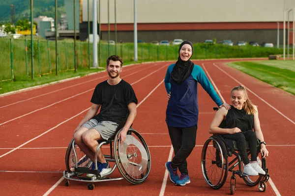 A woman with a disability in a wheelchair talking after training with a woman wearing a hijab and a man in a wheelchair.