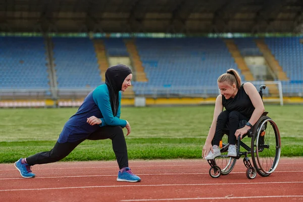 トラック上のマラソンレースのために彼らの体を伸ばし 準備車椅子にブルカを身に着けているイスラム教徒と他の1人の女性 — ストック写真