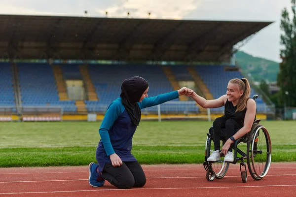 부르카를 착용하고 이슬람 마라톤 코스에서 훈련하는 휠체어에 장애가 친구를 지원한다 — 스톡 사진