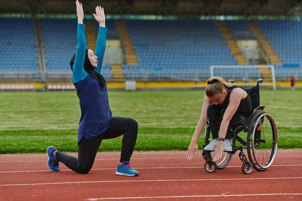 トラック上のマラソンレースのために彼らの体を伸ばし 準備車椅子にブルカを身に着けているイスラム教徒と他の1人の女性 — ストック写真