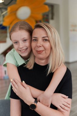 Küçük tatlı bir kız anaokulunda annesini öpüyor ve ona sarılıyor. Yüksek kalite fotoğraf