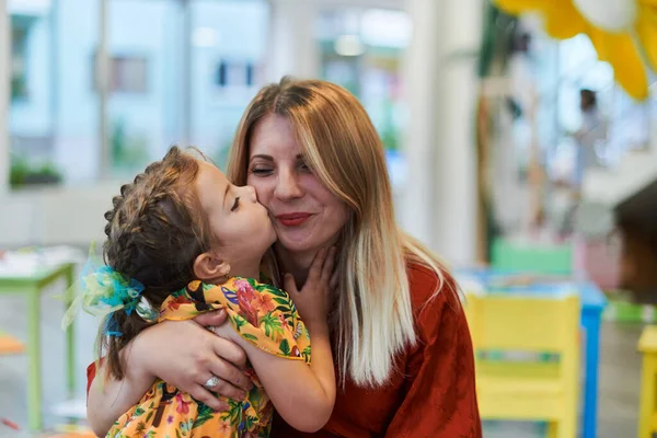 一个可爱的小女孩在幼儿园亲吻和拥抱她的母亲 高质量的照片 — 图库照片