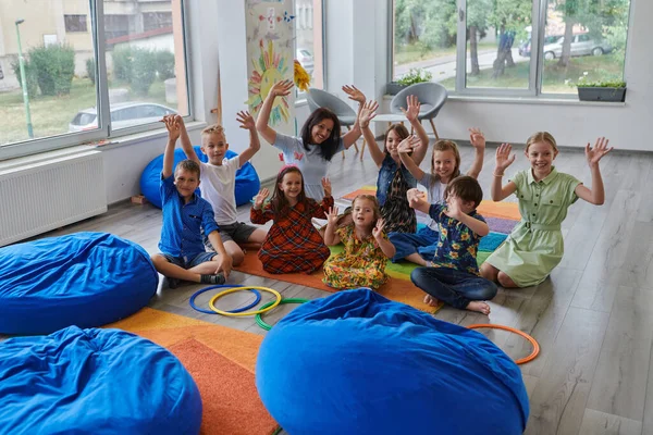 一位快乐的女教师与一群小学生坐在一起玩手游 — 图库照片