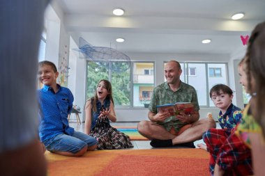 İlkokulda ya da anaokulunda okuma süresi, ilkokulda ya da anaokulunda çocuklara kitap okuyan bir öğretmen. Okul öncesi eğitim kavramı. Seçici odak.