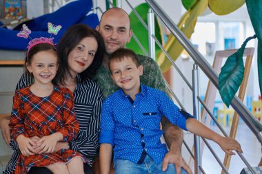 Portrait of a happy family. Photo of parents with children in a modern preschool classroom. Selective focus . High quality photo