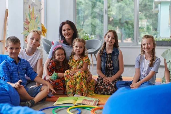一位快乐的女教师与一群小学生坐在一起玩手游 — 图库照片