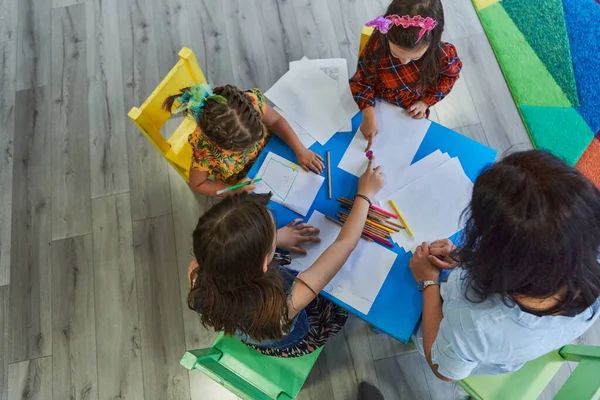 stock image Creative kids during an art class in a daycare center or elementary school classroom drawing with female teacher