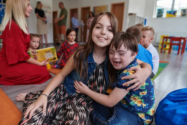 A girl and a boy with Downs syndrome in each others arms spend time together in a preschool institution.