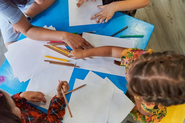 stock image Creative kids during an art class in a daycare center or elementary school classroom drawing with female teacher