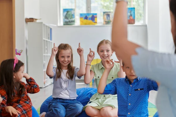 Счастливая Учительница Сидит Играет Ручные Игры Группой Маленьких Школьников — стоковое фото
