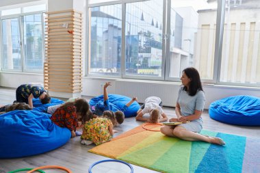 İlkokulda ya da anaokulunda okuyan bir öğretmen, bir ilkokulda ya da anaokulunda çocuklara kitap okur. Okul öncesi eğitim kavramı. Seçici odak.