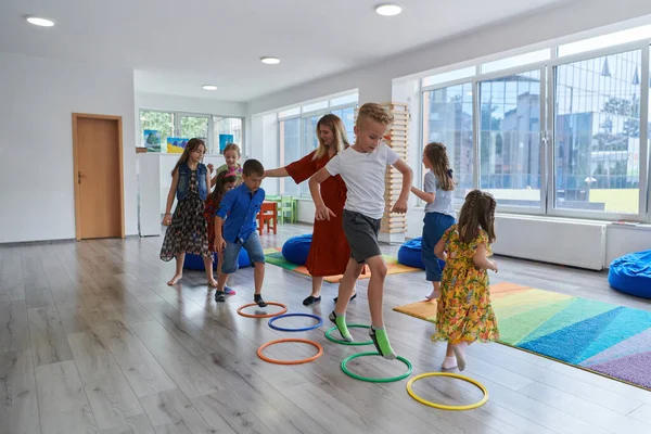 Små Förskolebarn Med Kvinnlig Lärare Golvet Inomhus Klassrummet Motionerar Hoppa — Stockfoto
