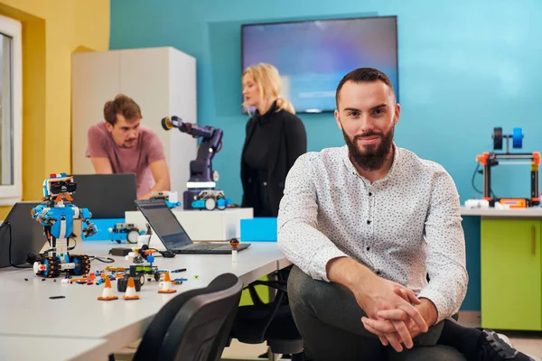 Hombre Sentado Laboratorio Robótica Mientras Sus Colegas Fondo Prueban Nuevos — Foto de Stock