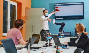 Robot laboratuvarında birlikte çalışan bir grup iş arkadaşı, robotik ve 3D yazıcıların karmaşık alanlarına odaklanıyor. Araştırmalarında yeniliğe olan adanmışlıklarını gösterirler.