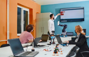Robot laboratuvarında birlikte çalışan bir grup iş arkadaşı, robotik ve 3D yazıcıların karmaşık alanlarına odaklanıyor. Araştırmalarında yeniliğe olan adanmışlıklarını gösterirler.