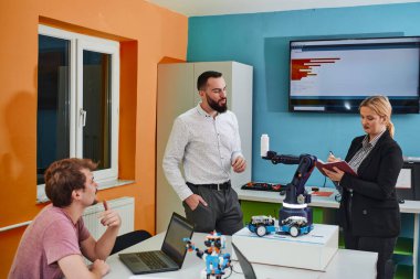 Robot laboratuvarında birlikte çalışan bir grup iş arkadaşı, robotik ve 3D yazıcıların karmaşık alanlarına odaklanıyor. Araştırmalarında yeniliğe olan adanmışlıklarını gösterirler.