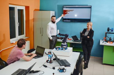Robot laboratuvarında birlikte çalışan bir grup iş arkadaşı, robotik ve 3D yazıcıların karmaşık alanlarına odaklanıyor. Araştırmalarında yeniliğe olan adanmışlıklarını gösterirler.