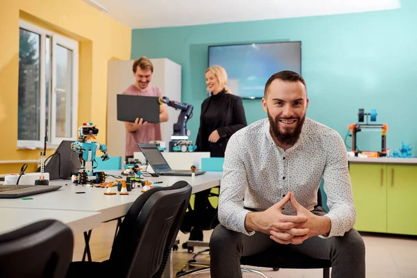 Ein Mann Sitzt Einem Roboterlabor Während Seine Kollegen Hintergrund Neue — Stockfoto