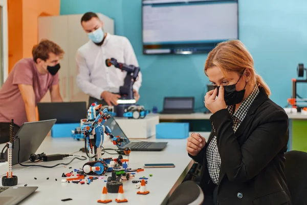 Женщина Защитной Маске Стоящей Лаборатории Пока Коллеги Тестируют Новое Роботизированное — стоковое фото