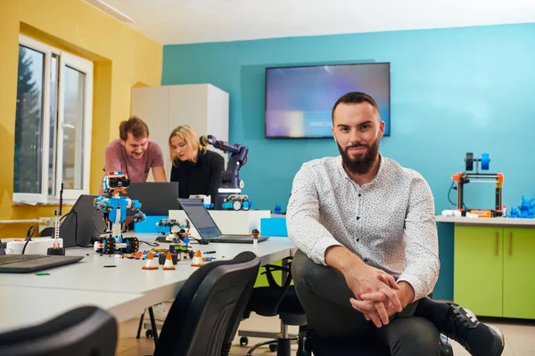 Muž Sedící Robotické Laboratoři Zatímco Jeho Kolegové Pozadí Testují Nové — Stock fotografie
