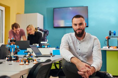 Robot laboratuarında çalışan bir adam, karmaşık robot bilimi ve 3D baskı alanlarına odaklanıyor. Araştırma, geliştirme, mühendislik gibi alanlarda kendilerini yeniliğe adadıklarını gösterirler.