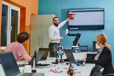 Robot laboratuvarında birlikte çalışan bir grup iş arkadaşı, robotik ve 3D yazıcıların karmaşık alanlarına odaklanıyor. Araştırmalarında yeniliğe olan adanmışlıklarını gösterirler.
