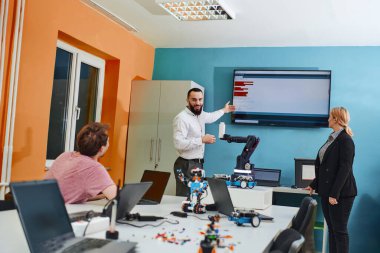 Robot laboratuvarında birlikte çalışan bir grup iş arkadaşı, robotik ve 3D yazıcıların karmaşık alanlarına odaklanıyor. Araştırmalarında yeniliğe olan adanmışlıklarını gösterirler.
