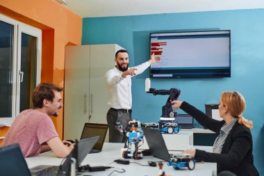 Robot laboratuvarında birlikte çalışan bir grup iş arkadaşı, robotik ve 3D yazıcıların karmaşık alanlarına odaklanıyor. Araştırmalarında yeniliğe olan adanmışlıklarını gösterirler.