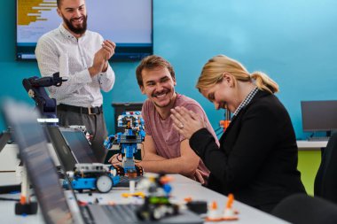 A group of colleagues working together in a robotics laboratory, focusing on the intricate fields of robotics and 3D printing. Showcase their dedication to innovation, as they engage in research clipart