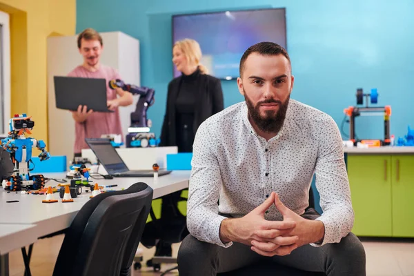 Ein Mann Sitzt Einem Roboterlabor Während Seine Kollegen Hintergrund Neue — Stockfoto