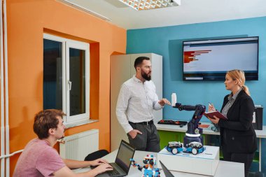 Robot laboratuvarında birlikte çalışan bir grup iş arkadaşı, robotik ve 3D yazıcıların karmaşık alanlarına odaklanıyor. Araştırmalarında yeniliğe olan adanmışlıklarını gösterirler.
